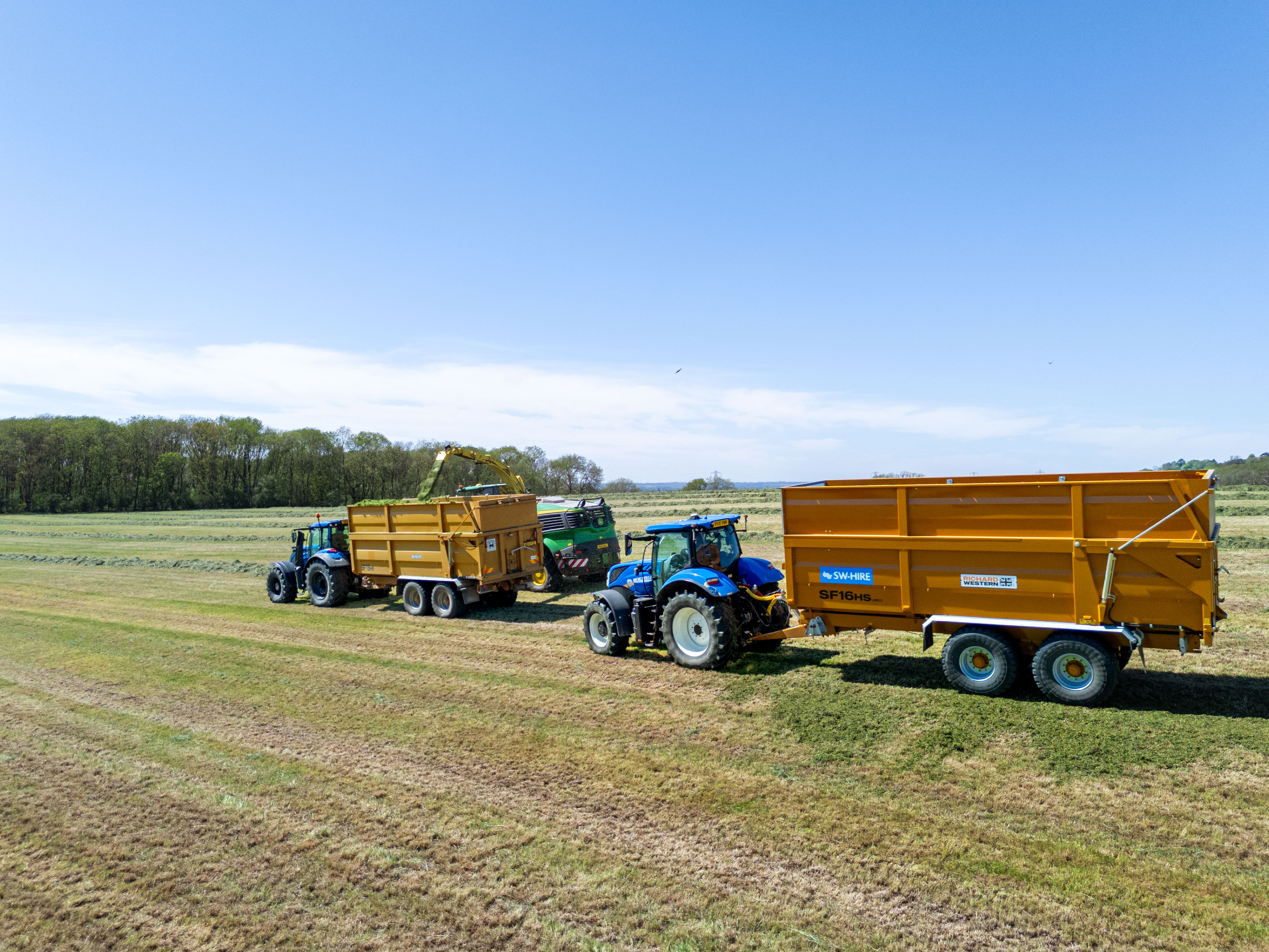 wed Richard Western Silage trailers toby a valtra and New Holland filling up with grass silage from a john deere forager